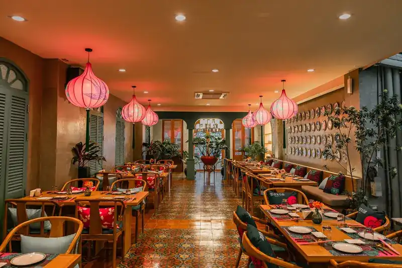 The dining room: patterned floor tiles, wooden tables, green shutters and pink lanterns