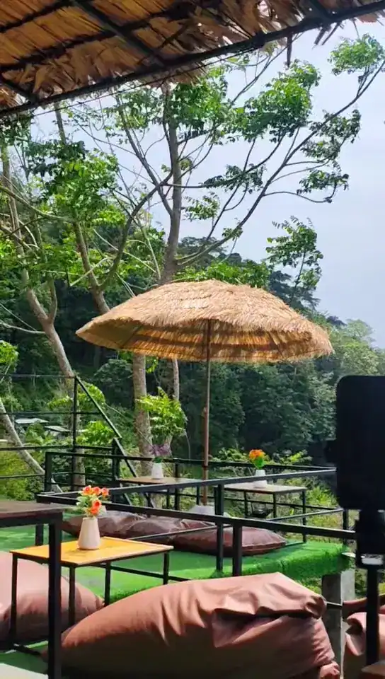 A thatched umbrella over low seats among the trees