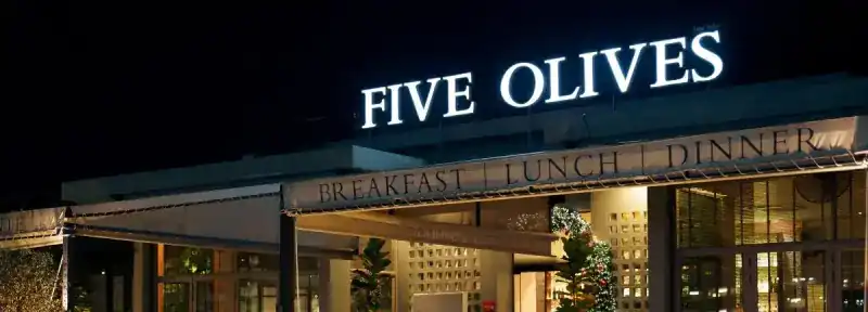 The lit Five Olives sign above the restaurant at night