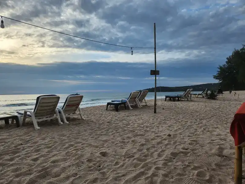 White sunbeds on Bang Tao Beach under a cloudy evening sky