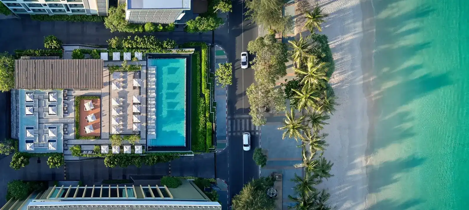 Aerial view of The Deck: the pool and loungers, Thawewong Road, Patong Beach and the sea