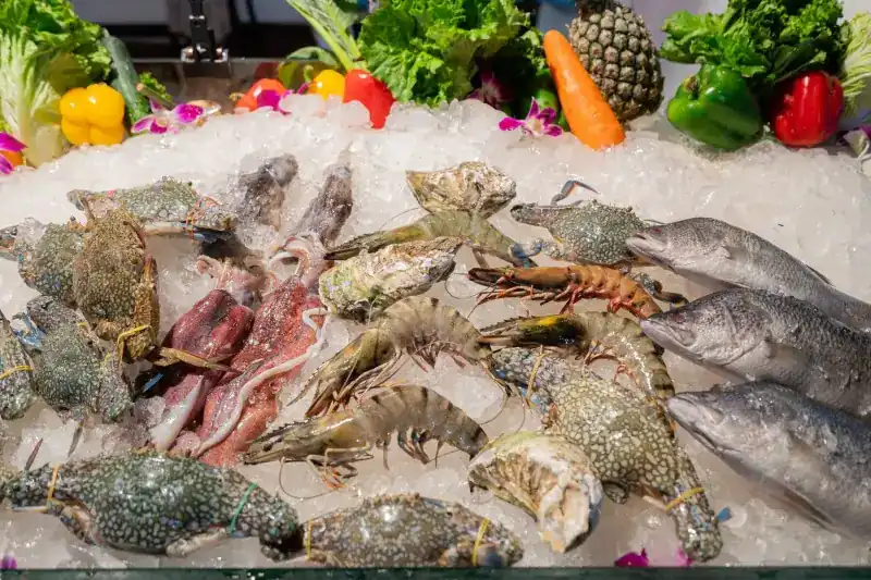 Crabs, prawns, squid and whole fish laid out on ice