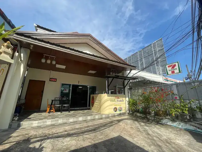 The shop front: a tiled roof, an open sliding door and the yellow counter, with a 7-Eleven sign next door