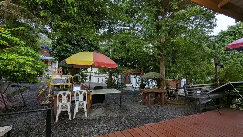 The garden by day: umbrellas, swings and a climbing frame on the gravel