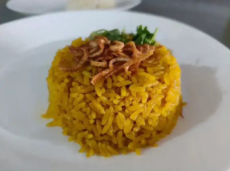 Close-up of the yellow rice, crowned with fried shallots and coriander