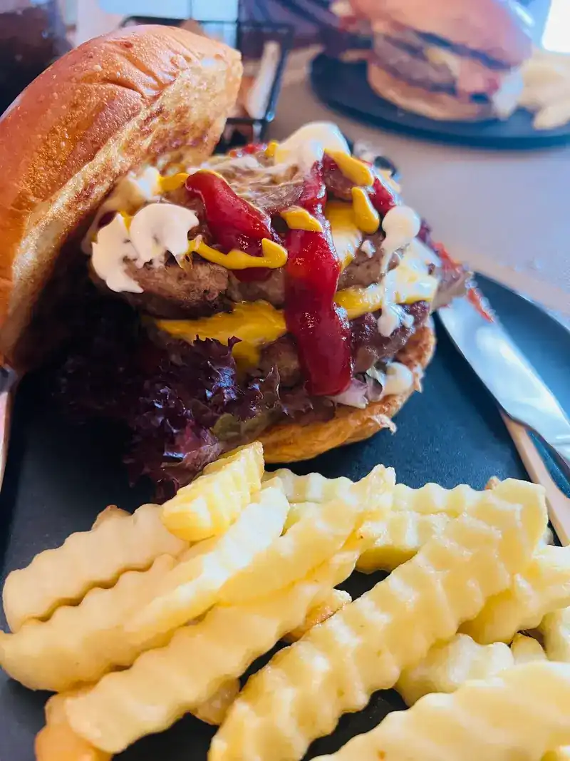 Burger with cheese, ketchup, mustard and mayonnaise, crinkle-cut fries in front