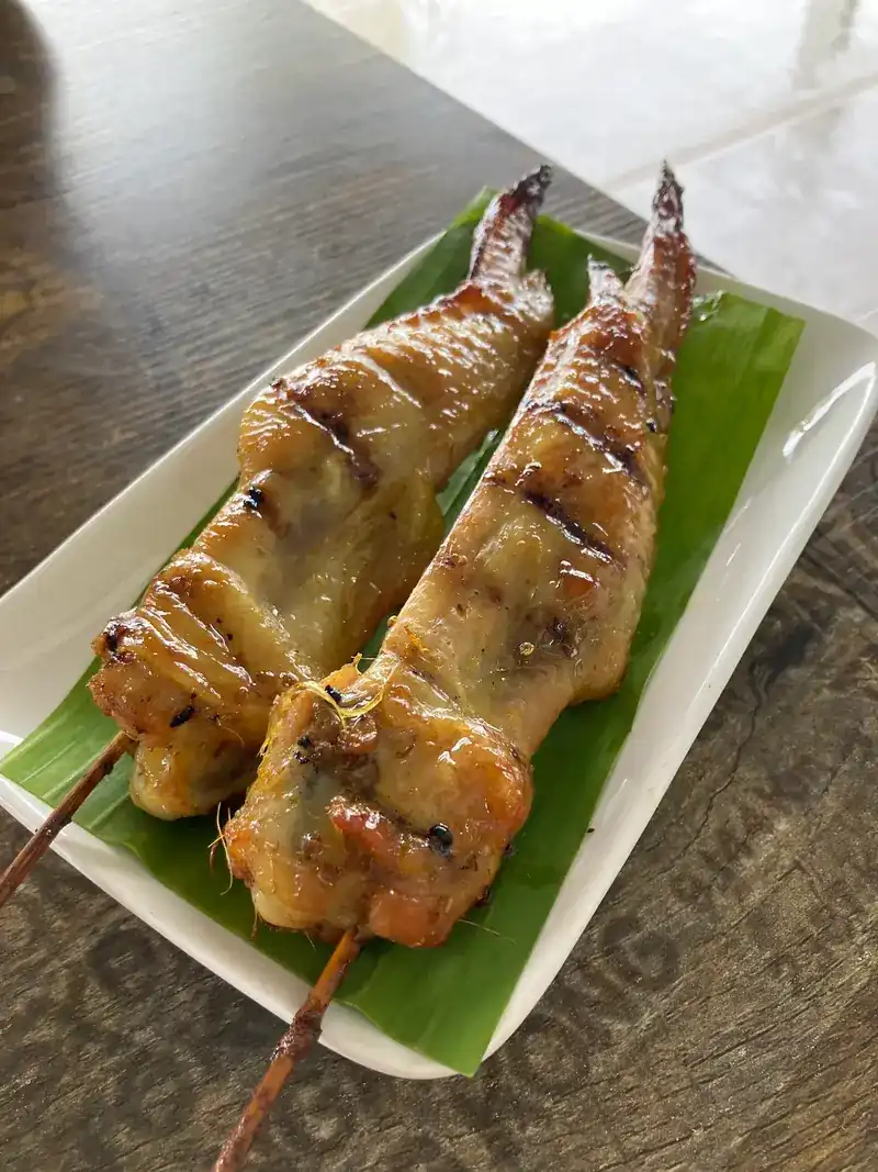 Grilled chicken on skewers, served on a banana leaf