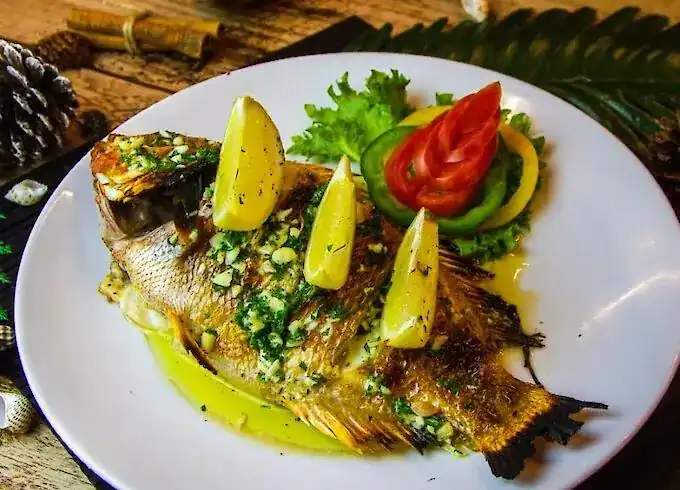 A whole fish with garlic, herbs and lemon wedges