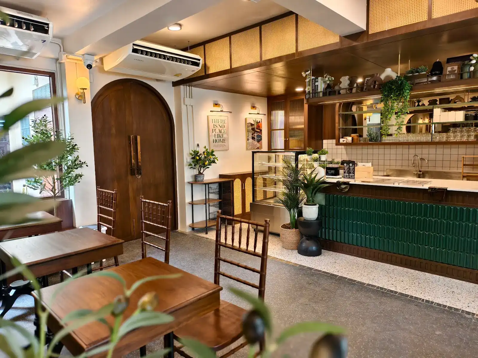 The café room at Haus Haus: wooden tables, an arched wooden door and the green-tiled counter