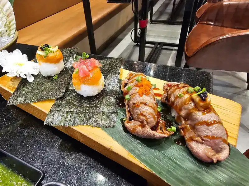 Sushi on nori squares and seared wagyu sushi on a wooden board