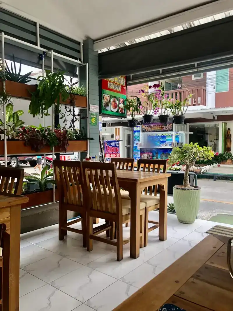 Wooden tables and a wall of plants at the open front, the street outside