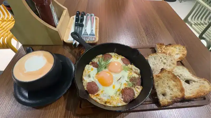 Eggs and sausage in a small skillet with toast and a latte