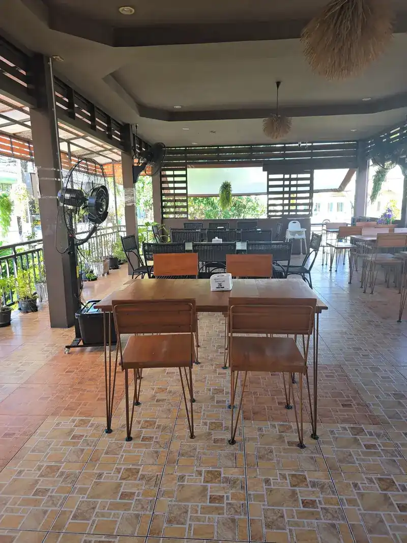 The covered terrace with wooden tables and plants along the rail