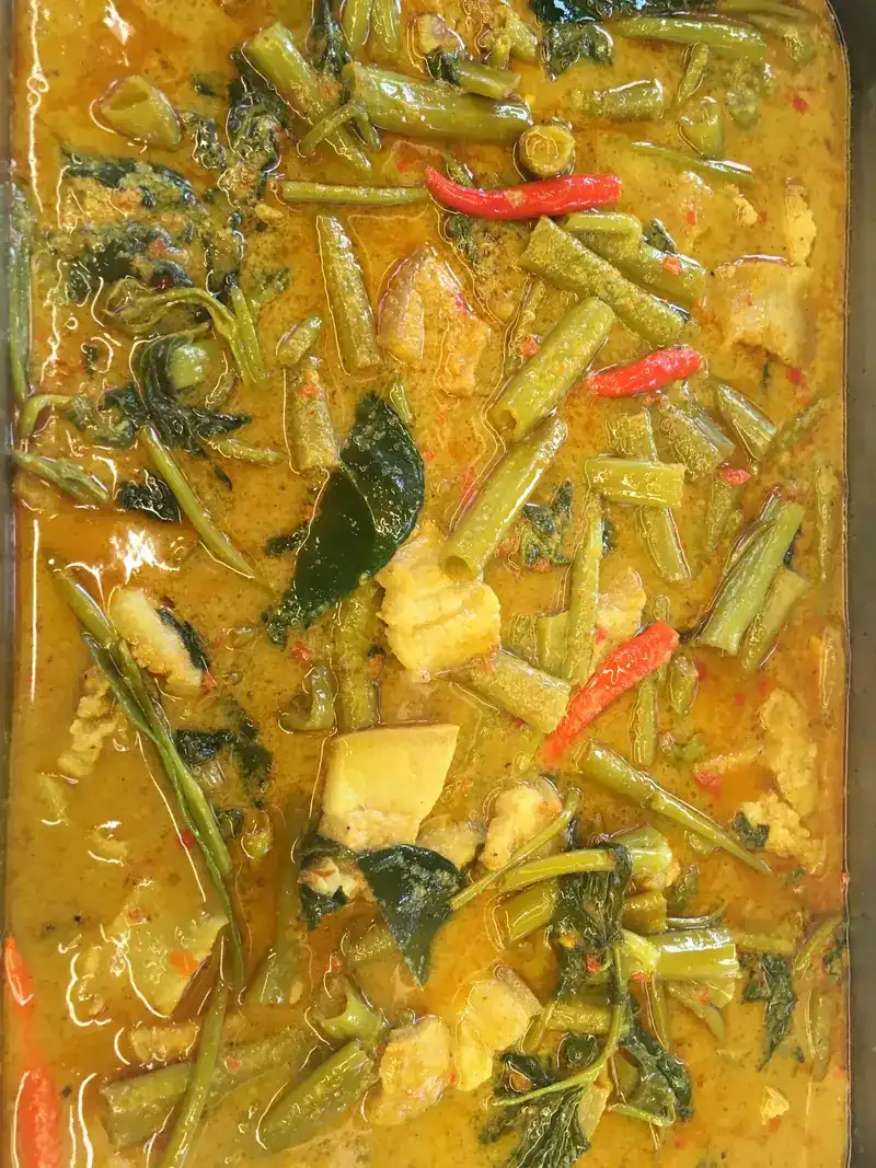 A yellow curry with long beans and greens