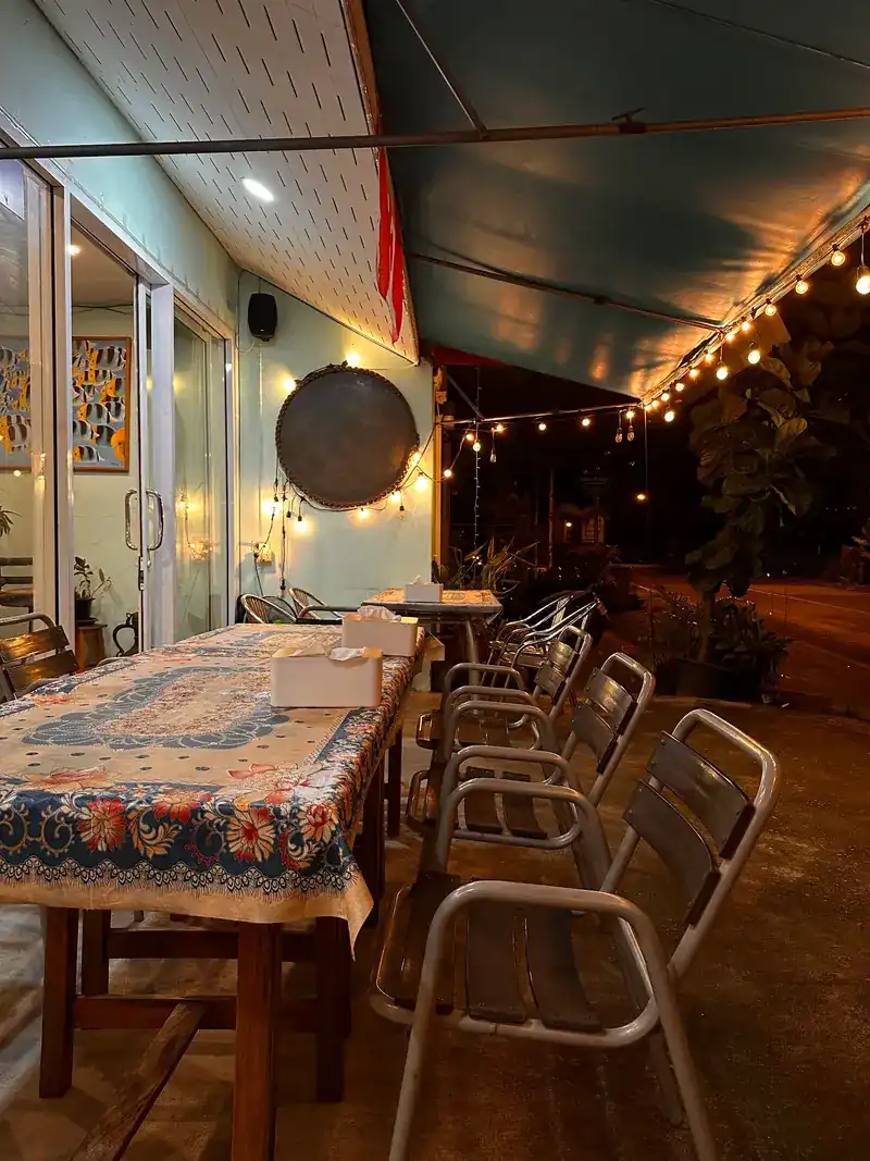 The terrace after dark: string lights under the awning and a long table in a flowered cloth