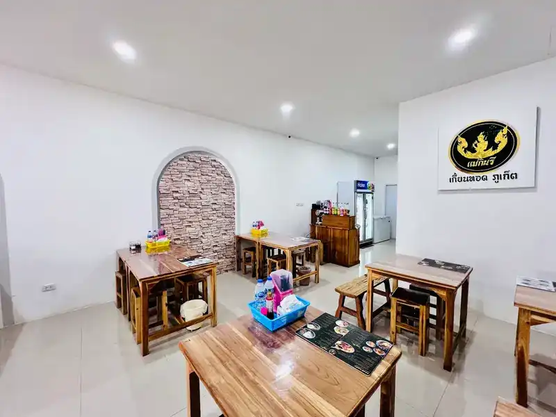 The room at branch 2: wooden tables, white walls and the gold Mae Kinnaree sign