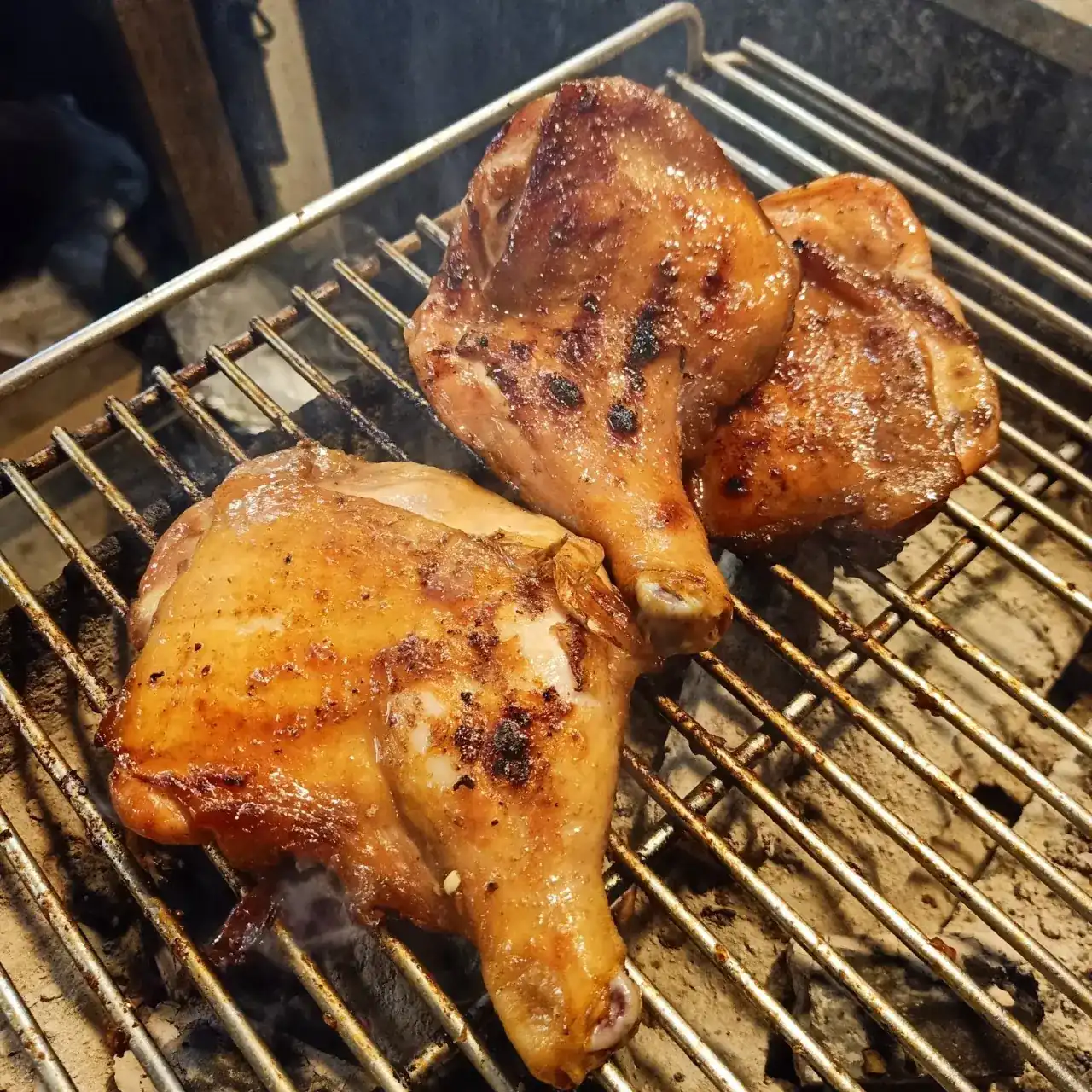 Chicken legs browning on a charcoal grill