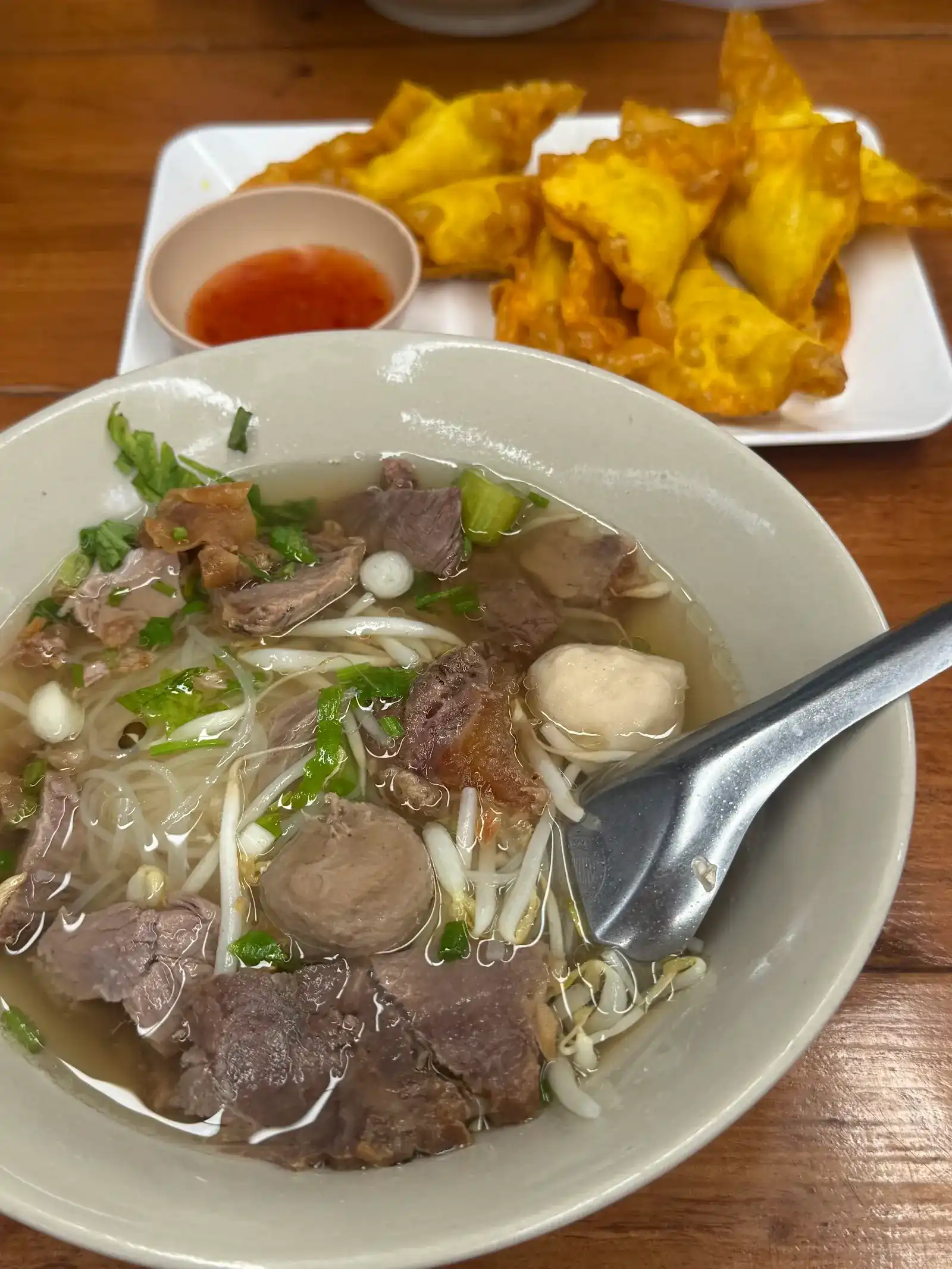 Beef noodle soup with beef balls, a plate of fried dumplings behind / ก๋วยเตี๋ยวเนื้อใส่ลูกชิ้น มีเกี๊ยวทอดวางอยู่ด้านหลัง
