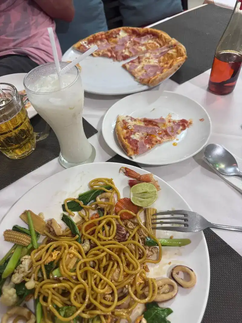 Pizza and stir-fried seafood noodles on the same table / พิซซ่าและเส้นผัดทะเลบนโต๊ะเดียวกัน