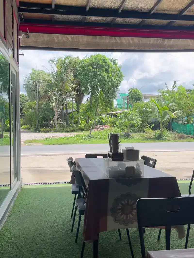 A table at the edge of the roof, looking out to the road and palms