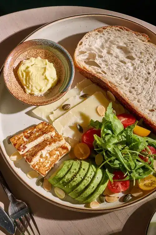 Sourdough, cheese, sliced avocado, rocket and tomatoes on a plate