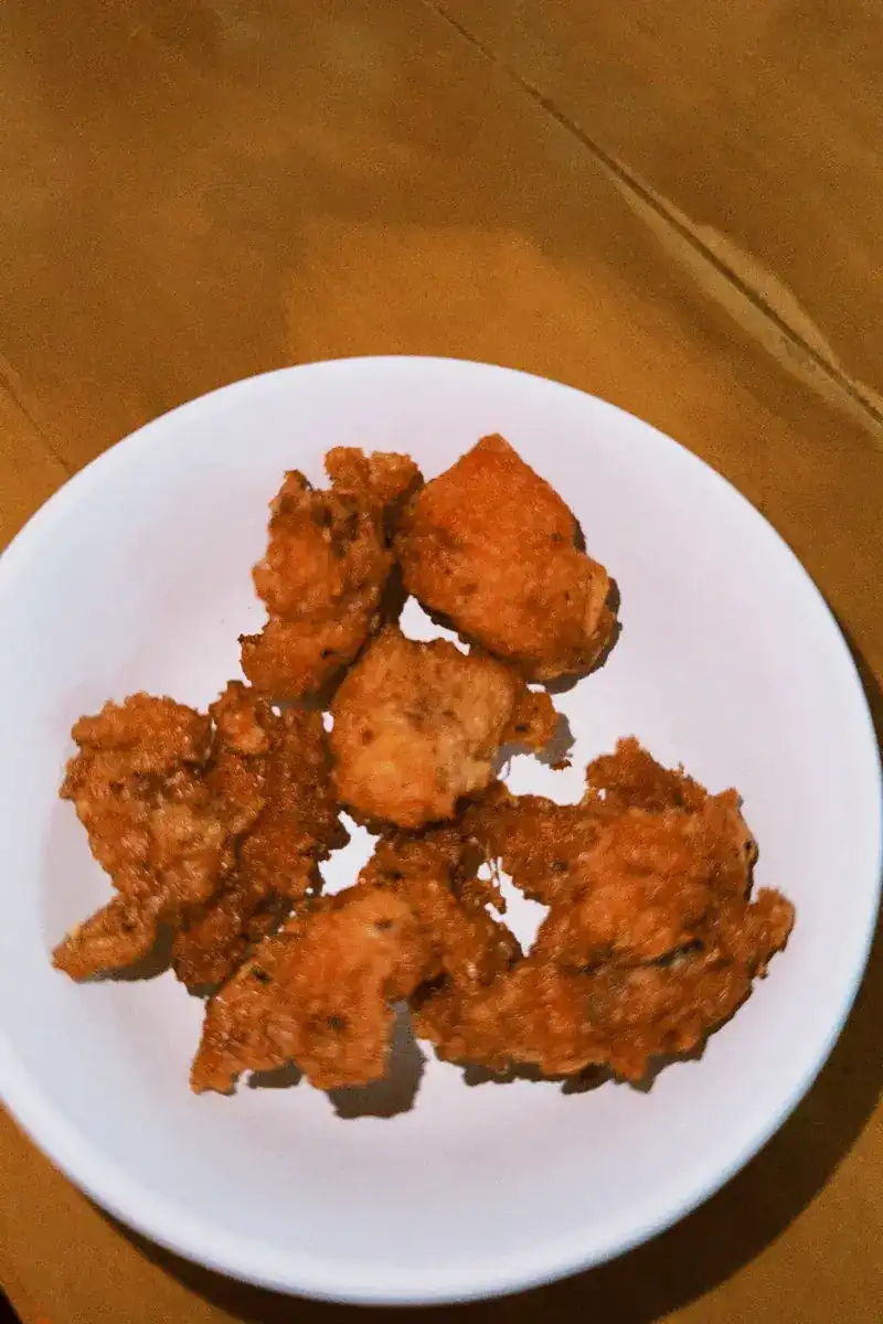 Bite-size pieces of fried chicken on a white plate on a wooden table