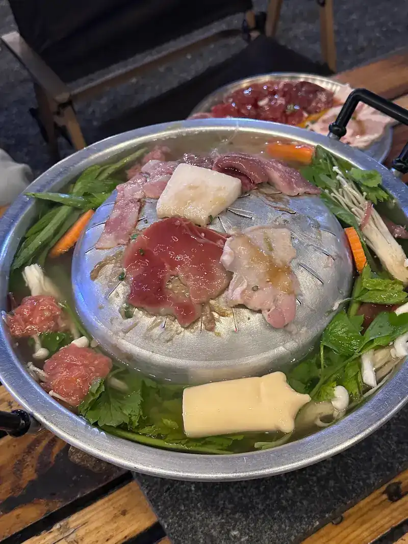 A mookata pan: meat on the hot dome, vegetables in the broth around it