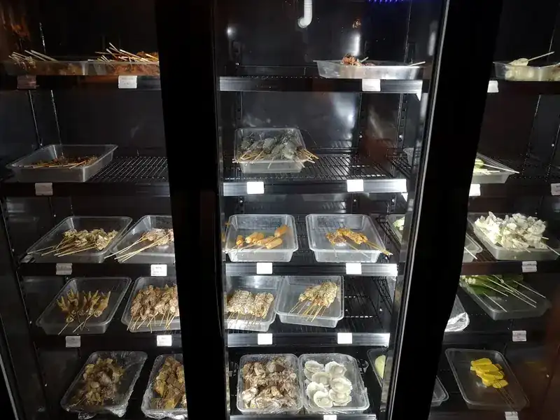 Glass fridges stacked with trays of skewers ready for the grill