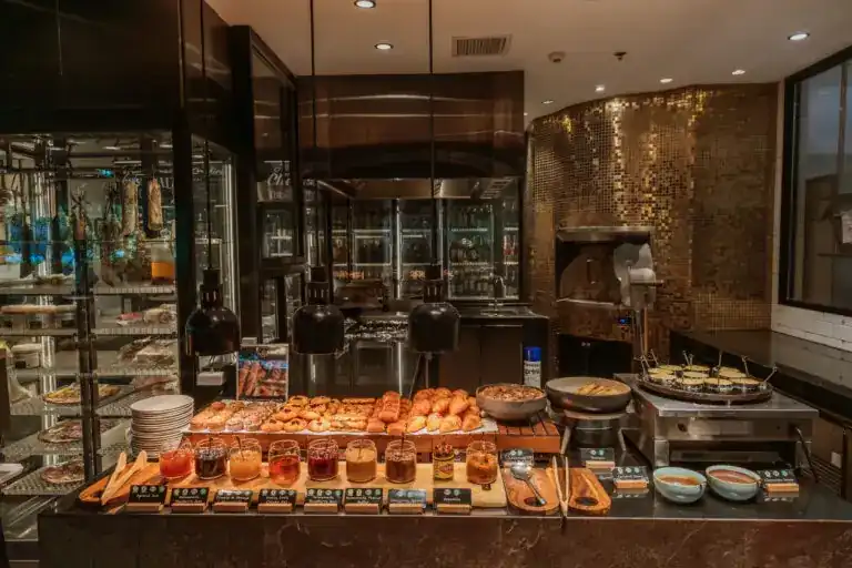 A counter of pastries and jams in front of a gold-tiled oven at Fresca