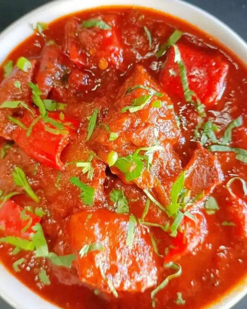 A rich red curry with peppers and fresh herbs