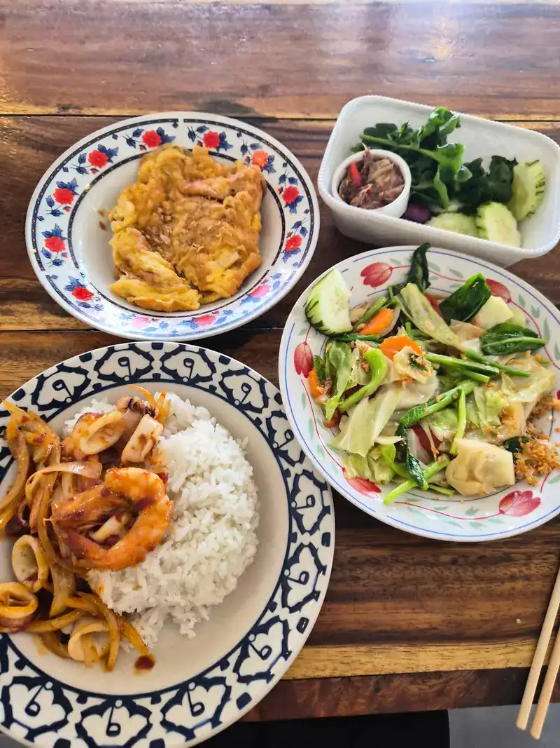 Rice with stir-fried squid and prawn, an omelette, stir-fried vegetables and a side of fresh greens