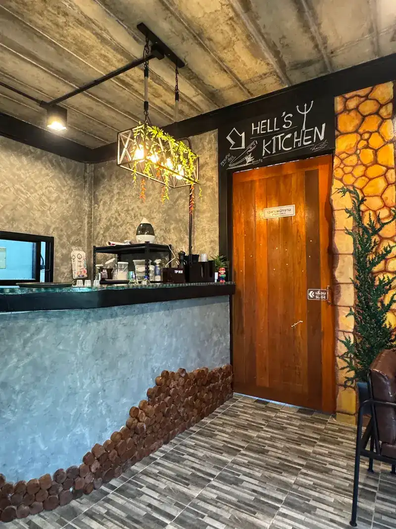 The grey plaster counter and a wooden kitchen door under a chalkboard that reads Hell's Kitchen