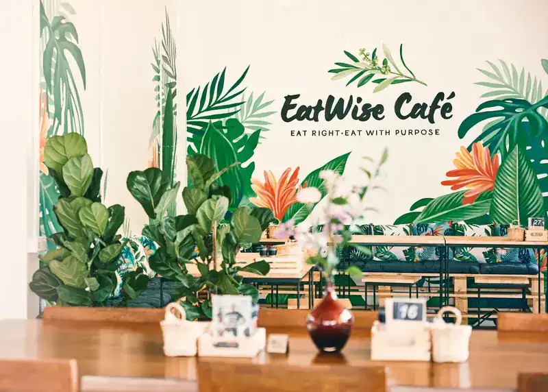 The painted leaf wall at EatWise Café, seen across a wooden table