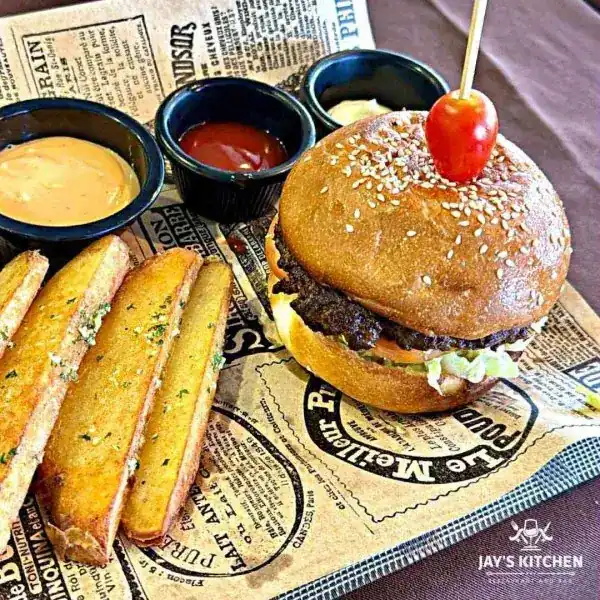 Burger with potato wedges and three dipping sauces