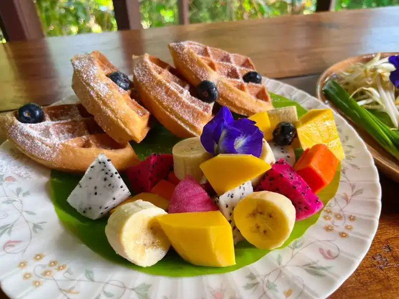 Waffles with mango, dragon fruit, banana, blueberries and a butterfly pea flower