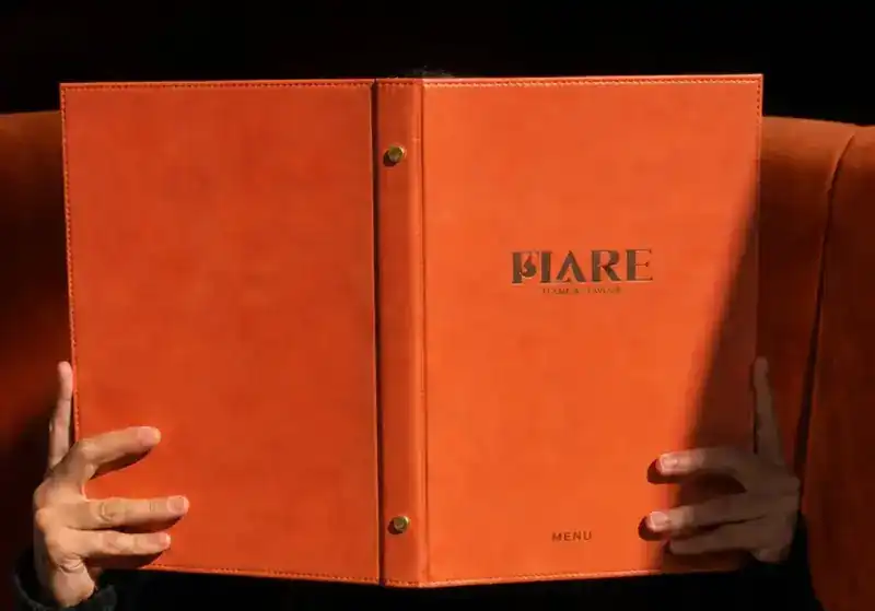Hands holding open the orange leather FLARE menu