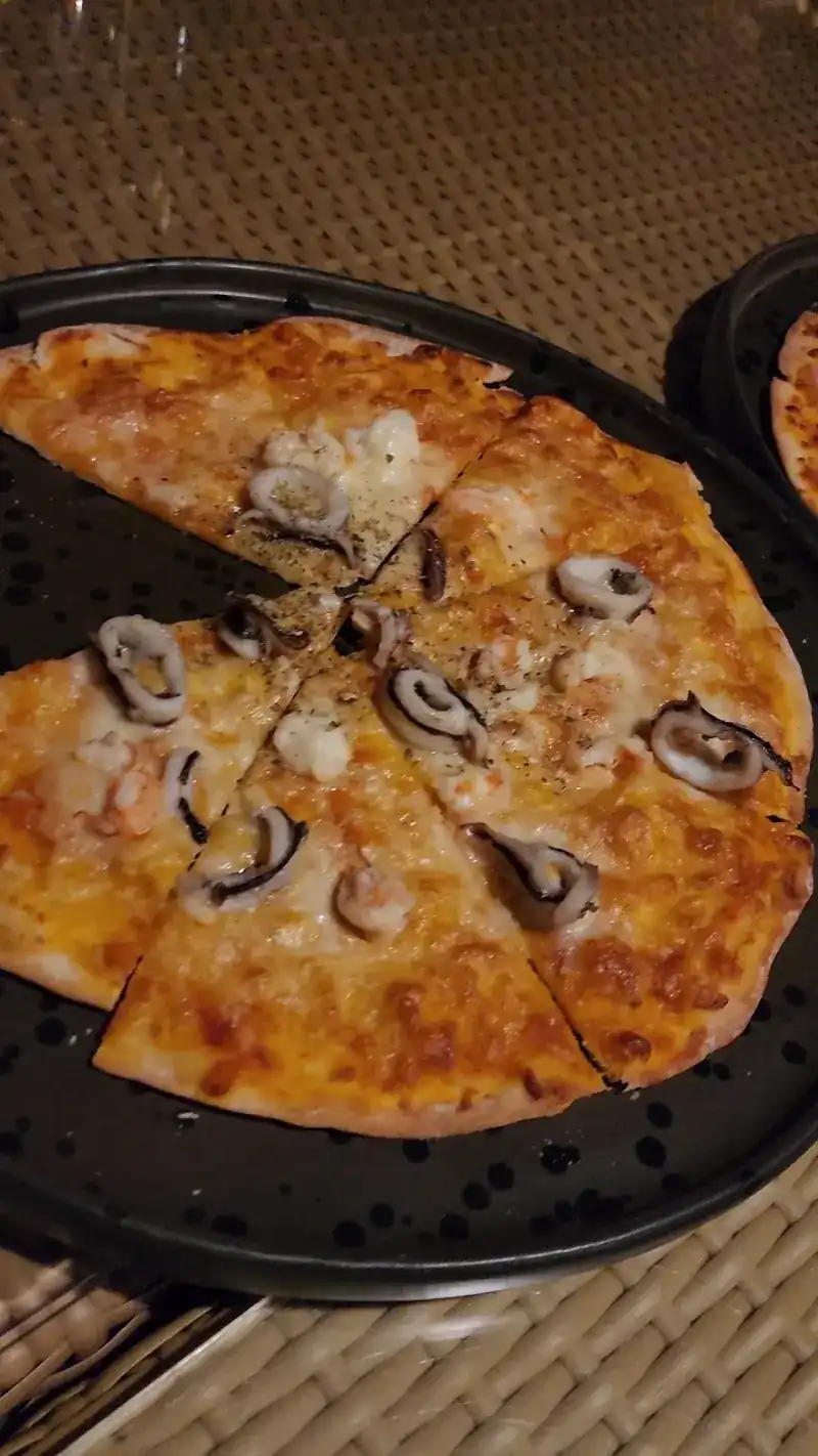 Seafood pizza with squid and prawns, cut into slices