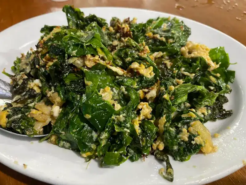 Leafy greens stir-fried with egg on a white plate