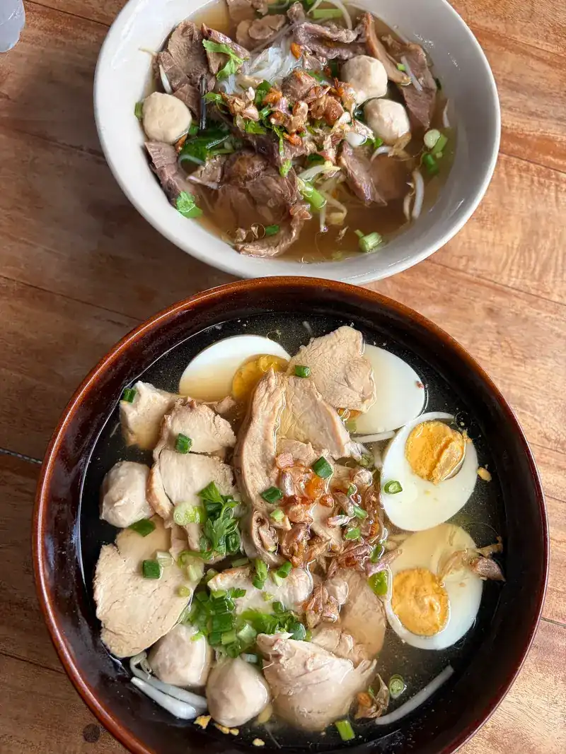 Two bowls of noodle soup, one with chicken, pork balls and boiled egg / ก๋วยเตี๋ยวสองชาม ชามหนึ่งใส่ไก่ ลูกชิ้นหมู และไข่ต้ม
