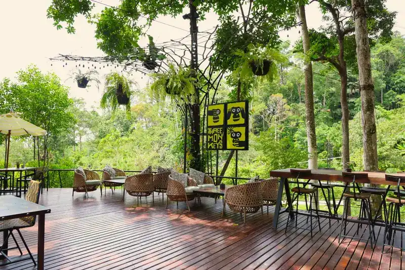 An open timber deck with woven armchairs looking out over the green valley