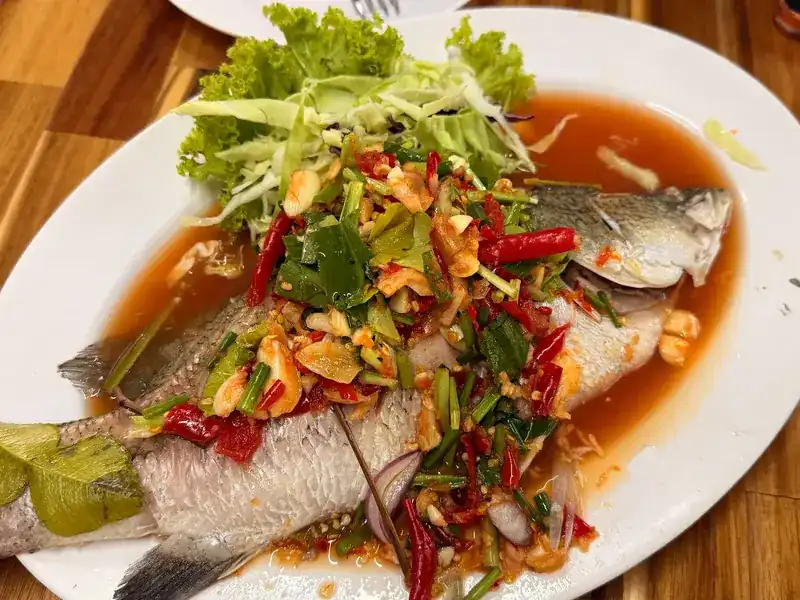 A whole fish under chilli, herbs and a red spicy sauce