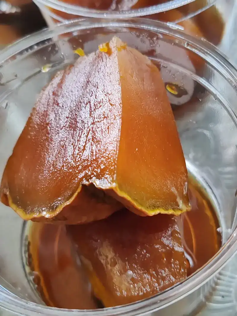Pieces of pumpkin glossy with syrup in a clear cup