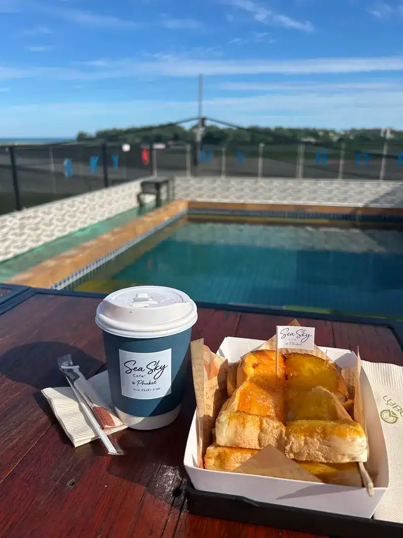 A hot coffee and toast on a table beside the rooftop pool