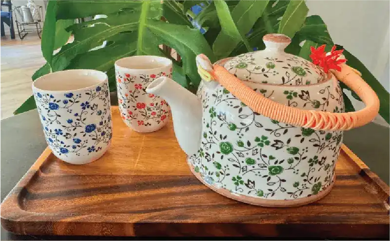 A flowered teapot and two cups on a wooden tray