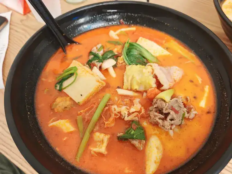 Mala tang in red broth with tofu, cabbage, sliced beef and greens