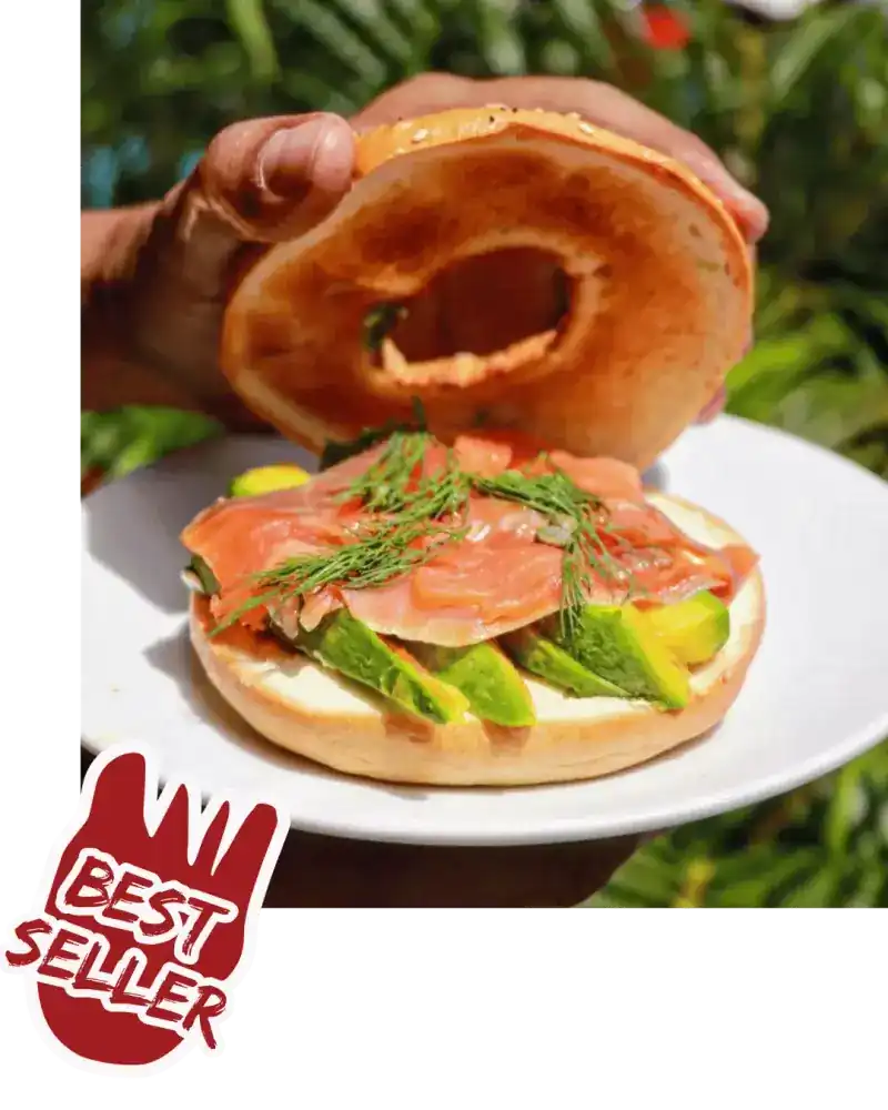 A toasted bagel opened over smoked salmon, avocado and dill