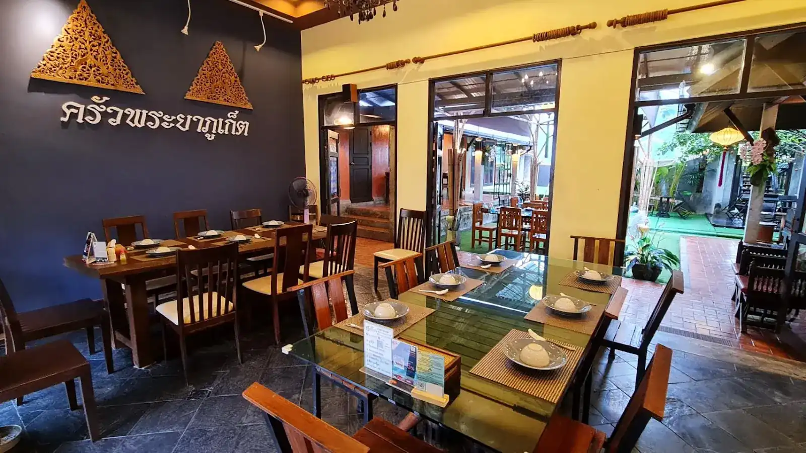 The indigo dining room at Krua Praya, two carved gold gables above the name ครัวพระยาภูเก็ต