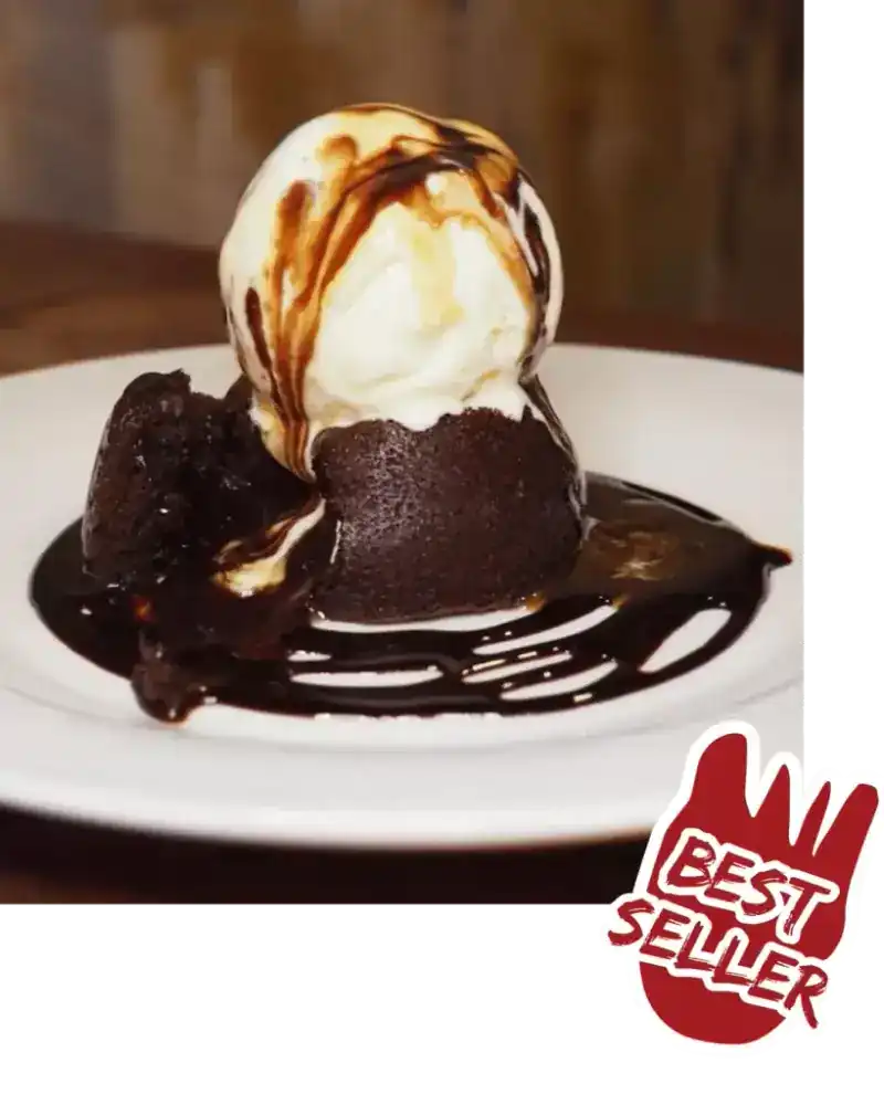 Chocolate lava cake under a scoop of ice cream with chocolate sauce