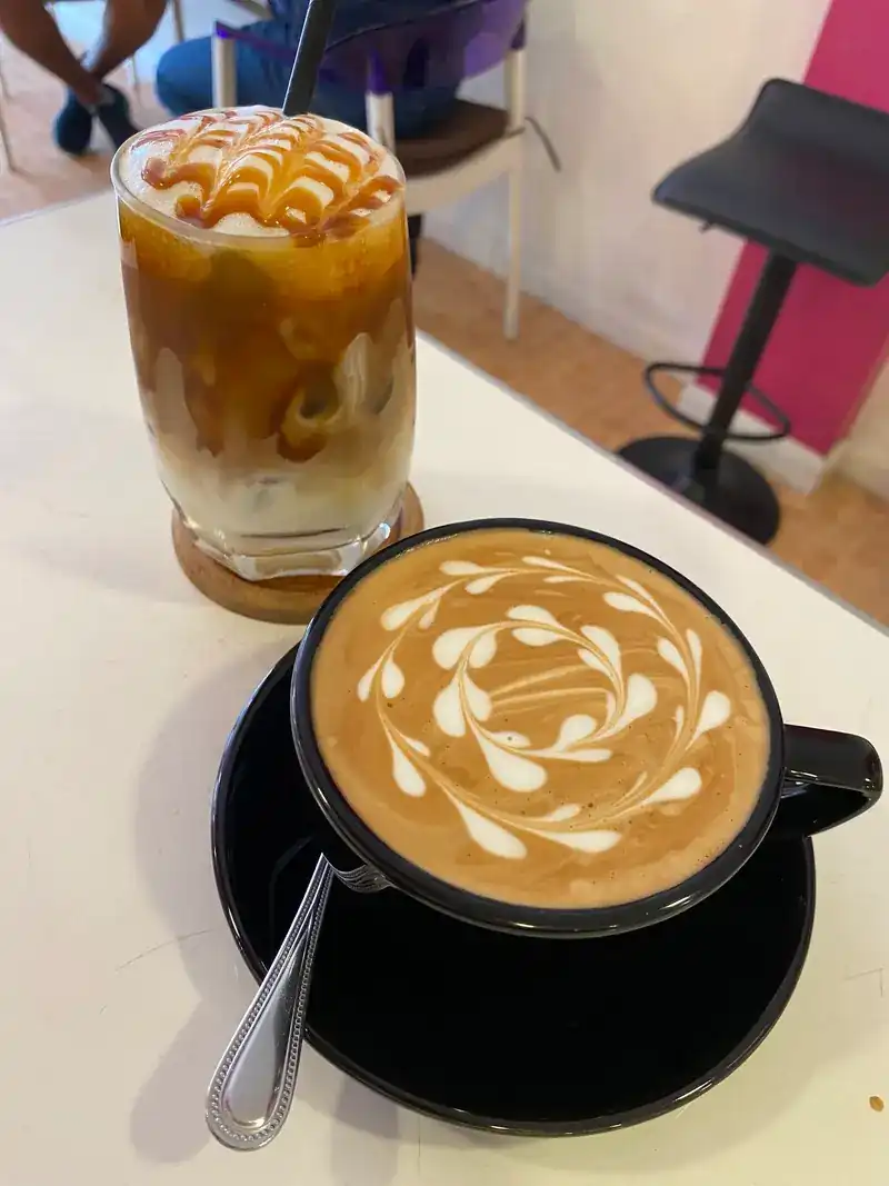 An iced coffee with caramel and a hot coffee with latte art