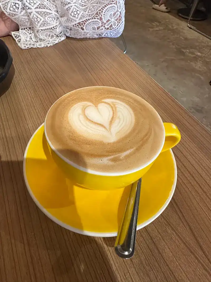 Hot coffee with latte art in a yellow cup and saucer